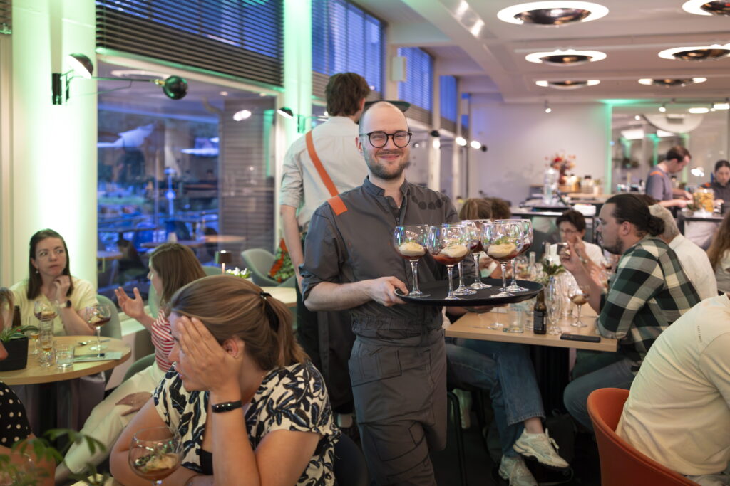 Člen personálu nese podnos se sklenicemi přes restauraci Zindering
